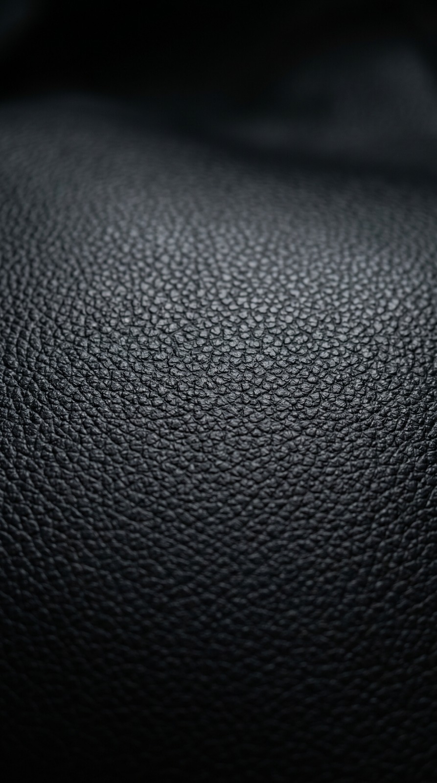 Curpiel premium — Macro de textura de curpiel premium color negro profundo, superficie uniforme, ligero brillo satinado, sobre fondo dark